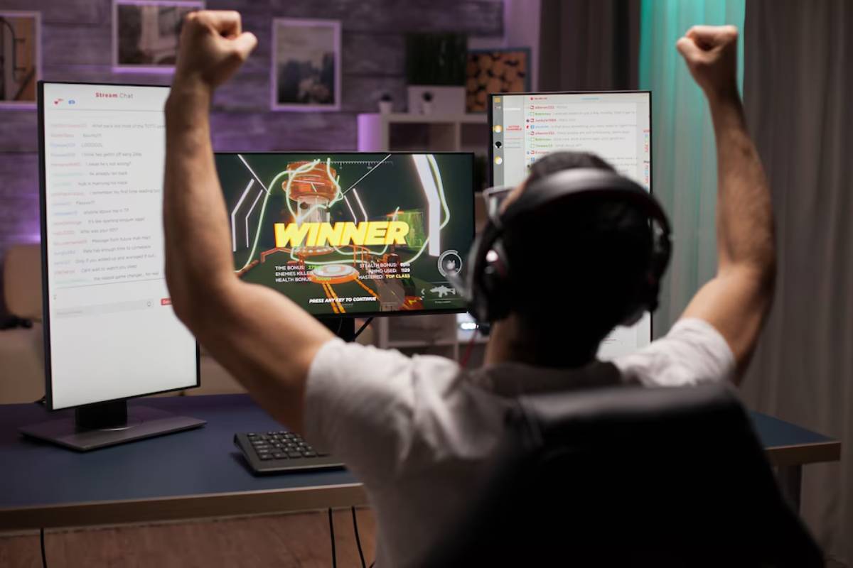 A gamer with headphones raises a fist in celebration as the screen displays WINNER after a successful game.