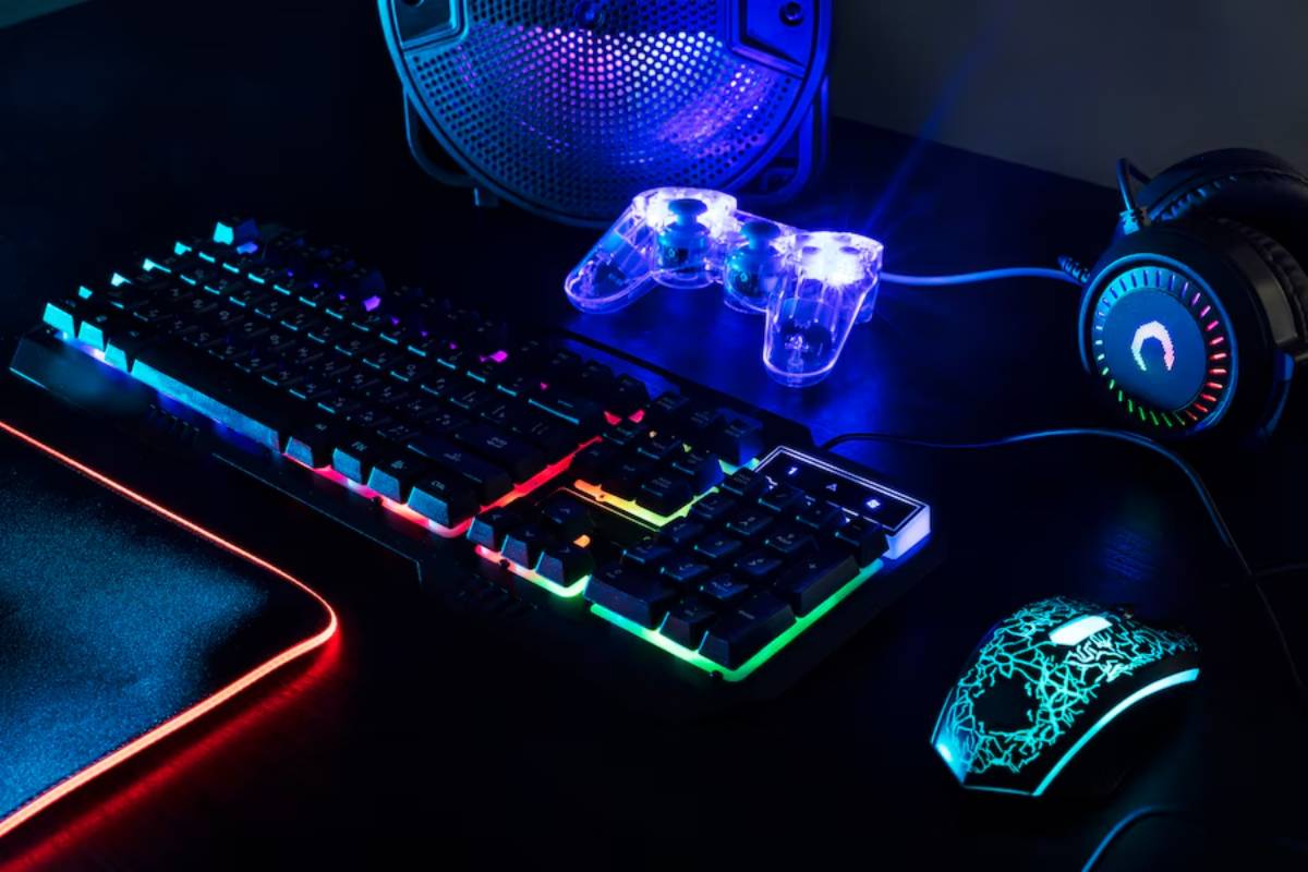 A gaming setup featuring a vibrant RGB keyboard, illuminated gaming mouse, glowing game controller, headphones, and a speaker on a dark surface.