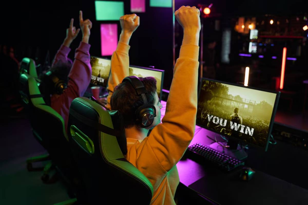 Two excited gamers celebrate victory, raising their arms in triumph, with
