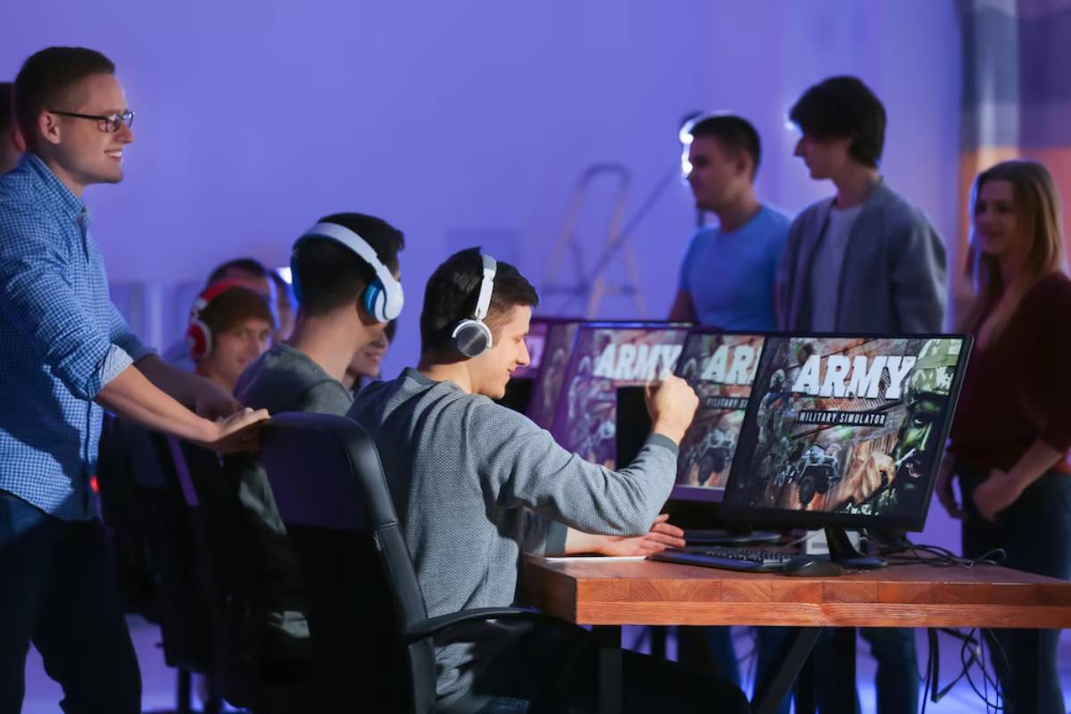 A group of individuals in a dimly lit space engaging with gaming monitors displaying an 