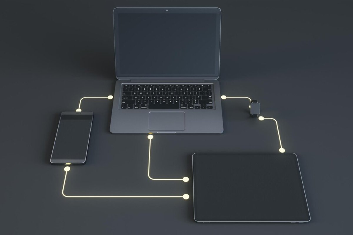 A laptop connected to a smartphone and tablet with glowing lines, illustrating a digital network or charging setup.