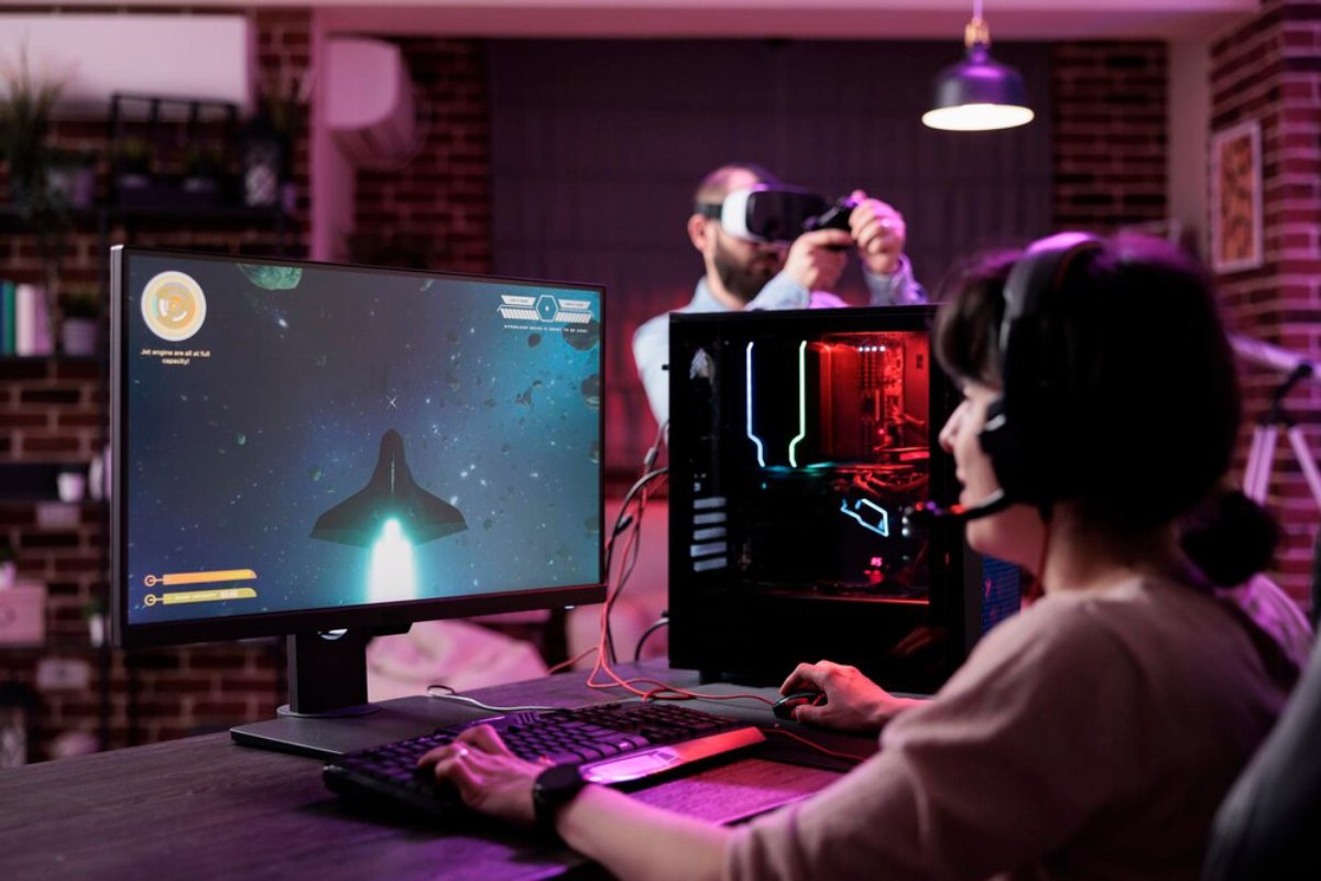 A person plays a space-themed video game on a computer, showcasing a vibrant game display and a glowing gaming PC in a cozy room.