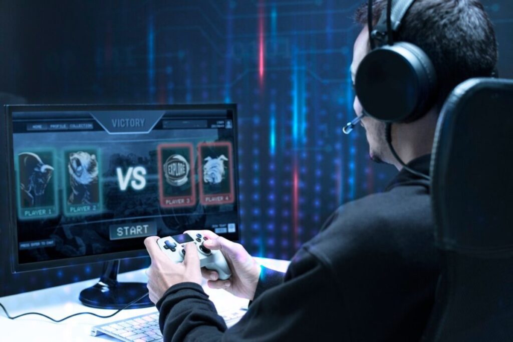 A gamer wearing a headset plays on a console, facing a monitor displaying a victory screen in a competitive match setup.